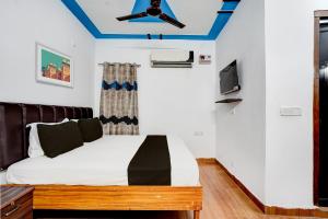 OYO Premier Jim Corbett Home Stay في رامناجار: غرفة نوم مع سرير ومروحة سقف