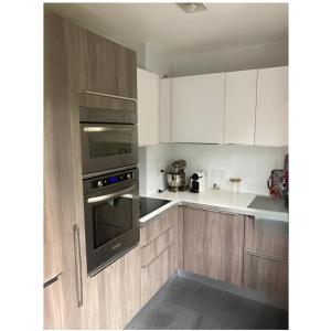a kitchen with white cabinets and a black oven at Appartement Cosy- Emplacement Idéal pour les JO ! in Vanves