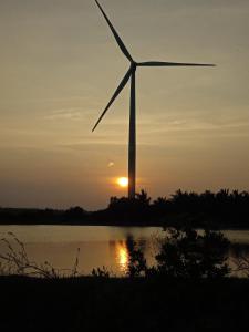 un molino de viento frente a un lago con la puesta de sol en Rangani Lagoon Resort, en Kalpitiya