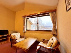 ペンション湖風 في تاتيشينا: غرفة بطاولة وكرسيين ونافذة