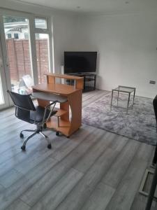 una oficina con escritorio, silla y TV en The w3 flat en Londres