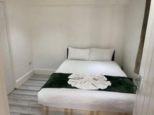 1 dormitorio con 1 cama blanca con manta verde en The w3 flat en Londres