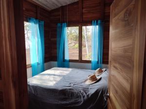 1 dormitorio con 1 cama con cortinas azules y ventana en Casa Lagarto Beachfront, en Venado