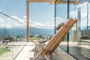 a wooden rocking chair on a balcony with a view at Hotel Ambet in Maranza
