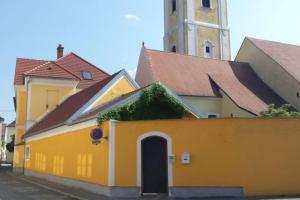 een geel gebouw met een klokkentoren op de achtergrond bij Wachau - Angenehm ruhiges Zimmer 5 in Mautern