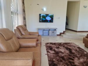 a living room with two chairs and a couch and a tv at Flix holdings- Apa apartments mombasa in Mombasa