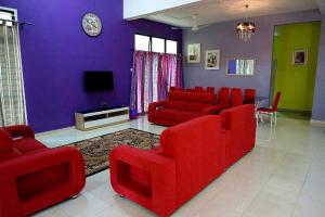 uma sala de estar com cadeiras vermelhas e uma parede roxa em Anugerah Homestay Muslim private pool 5 bilik em Kampong Padang Keladi
