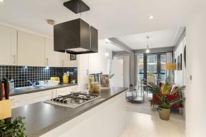 a kitchen with white cabinets and a stove top oven at LiveStay - Modern Two Bed Apartment in Stratford in London
