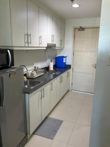 - une cuisine avec des placards blancs, un évier et une porte dans l'établissement SEA Residences in Pasay near Mall of Asia 2BR and 1BR, à Manille