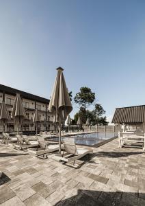 einen Pool mit Stühlen und Sonnenschirmen neben einem Gebäude in der Unterkunft VILLA DIANA in Solotwyno