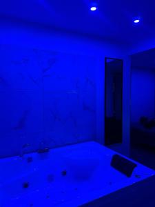 a blue room with a tub and a mirror at Lov’SPA 2 in Fleury-Mérogis