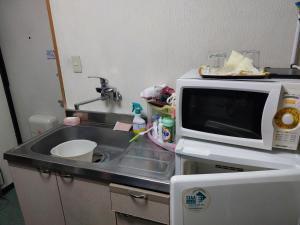 a kitchen counter with a sink and a microwave at 四万川 in Yaochō