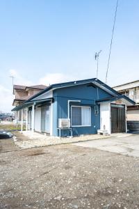 uma casa azul sentada ao lado de uma rua em かぐら庵 em Kitakata