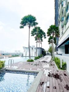 Una piscina con sillas y palmeras al lado de un edificio. en Kajang Oasis@MKH Boulevard, en Kajang