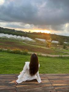 una mujer sentada en una mesa viendo la puesta de sol en TODO Farm - Organic Farming & Retreat, en Phu Yen