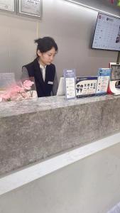 een vrouw die aan een toonbank in een boekwinkel zit bij Rose International Hotel in Shanghai