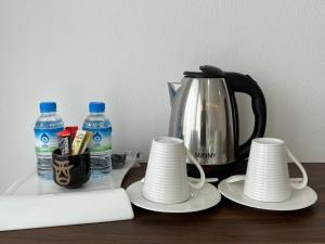 a tea kettle and cups on a table with water bottles at Remember Hotel in Ban Khouaphan