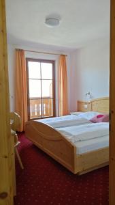 Cama grande de madera en habitación con ventana en Oberlindnerhof en San Lorenzo di Sebato