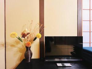 a vase with flowers on a table next to a tv at Rakuyado kyotofushimi II in Kyoto