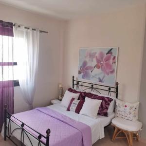 Schlafzimmer mit einem Bett mit lila Bettwäsche und einem Stuhl in der Unterkunft ARKASA KARPATHOS SEAFRONT PARADISOS in Karpathos
