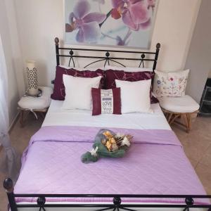 ein Bett mit lila Laken und einer Schale Obst darauf in der Unterkunft ARKASA KARPATHOS SEAFRONT PARADISOS in Karpathos