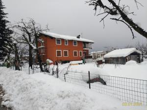 an orange house is covered in snow at Nonna Evy in Pergine Valsugana