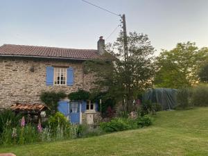 Oradour-sur-Vayres的住宿－Tardoire cottage，一座带蓝色窗户和庭院的老砖屋