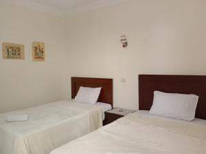 two beds in a room with white sheets at Giza Pyramids View Apartment in Cairo