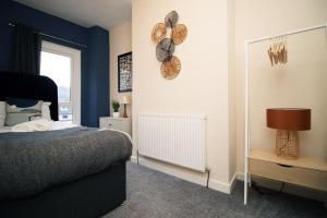 Schlafzimmer mit blauen Wänden, einem Bett und einem Spiegel in der Unterkunft Cosy 3BR Home, Scenic Views, Ideal for Walks & Work in Abertillery