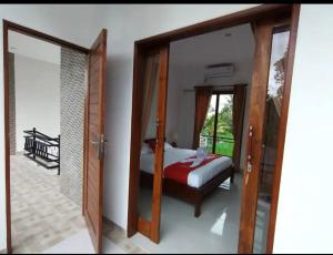 Schlafzimmer mit einem Bett und einer Glasschiebetür in der Unterkunft Belvilla 93800 The Abhinaya Villa Near Central Ubud in Payangan
