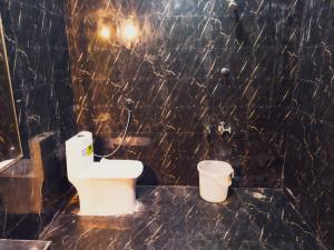 a black tiled bathroom with a toilet and a bucket at Hotel Hara Rama Hare Krishna Rameswaram in Rāmeswaram