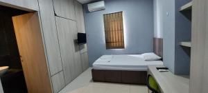 OYO 93808 Lincoln Dormitory في تانغيرانغ: غرفة صغيرة بها سرير ونافذة