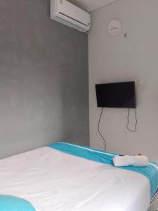 een slaapkamer met een bed en een tv aan de muur bij OYO 93808 Lincoln Dormitory in Tangerang