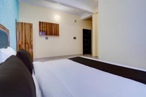 OYO HOTEL STAY INN في هالدوانى: غرفة نوم بسرير ابيض في غرفة