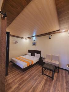 Schlafzimmer mit einem Bett, einem Tisch und Stühlen in der Unterkunft Hotel Hidden Chalet Nainital Near Mall Road - Luxury Room - Excellent Customer Service in Nainital