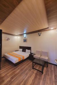 Schlafzimmer mit einem Bett, einem Tisch und Stühlen in der Unterkunft Hotel Hidden Chalet Nainital Near Mall Road - Luxury Room - Excellent Customer Service in Nainital