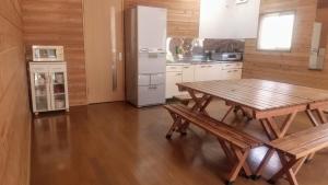 a kitchen with a wooden table and a refrigerator at のんびれっじ　心和（ここわ）棟 in Shiozawa