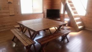 una mesa de madera y bancos en una habitación en のんびれっじ　心和（ここわ）棟 en Shiozawa
