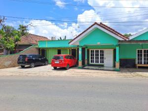 une voiture rouge garée devant une maison verte dans l'établissement OYO 93814 Amanda Homestay, à Bandar Lampung