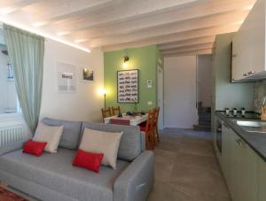 uma sala de estar com um sofá cinzento e uma cozinha em Mamma Ciccia - modern apt in the historic centre em Mandello del Lario