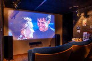 una pantalla grande con una foto de un hombre y una mujer en Cinéma Enchanté (maison d'hôtes avec écran géant) en Prez-vers-Siviriez