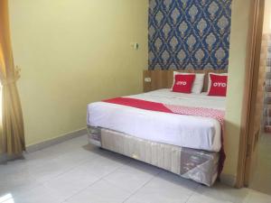 a bedroom with a bed with red pillows on it at OYO 93818 Wisma Al Araf Syariah in Palembang