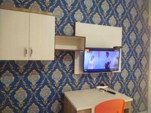 een kamer met een bureau en een tv aan de muur bij OYO 93818 Wisma Al Araf Syariah in Palembang