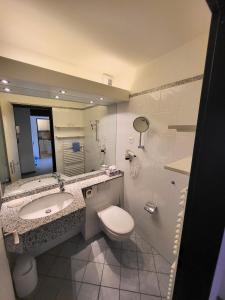 een badkamer met een wastafel, een toilet en een spiegel bij Hotelwohnung Superior-Suite in Beatenberg