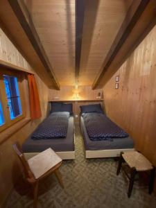 um pequeno quarto com 2 camas e uma cadeira em Haus Maran em Urmein