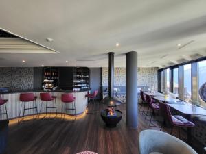 a restaurant with a bar with red chairs and tables at Alpine Luxury Suite Beatenberg in Beatenberg