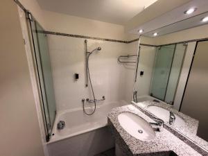 a bathroom with a sink and a shower and a tub at Hotelwohnung Superior-Suite in Beatenberg