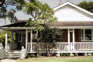 une maison avec une véranda blanche et un arbre dans l'établissement The Whitehouse on Boyce Street, à Taree