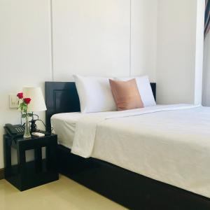 um quarto com uma cama grande com lençóis brancos e almofadas em Phuong Dong Hotel and Apartment em Quy Nhon