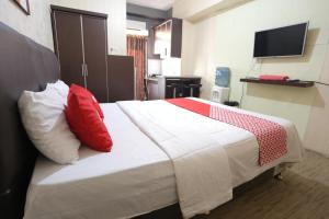 a bedroom with a bed with red and white pillows at OYO 93825 Nona Key Property in Bekasi